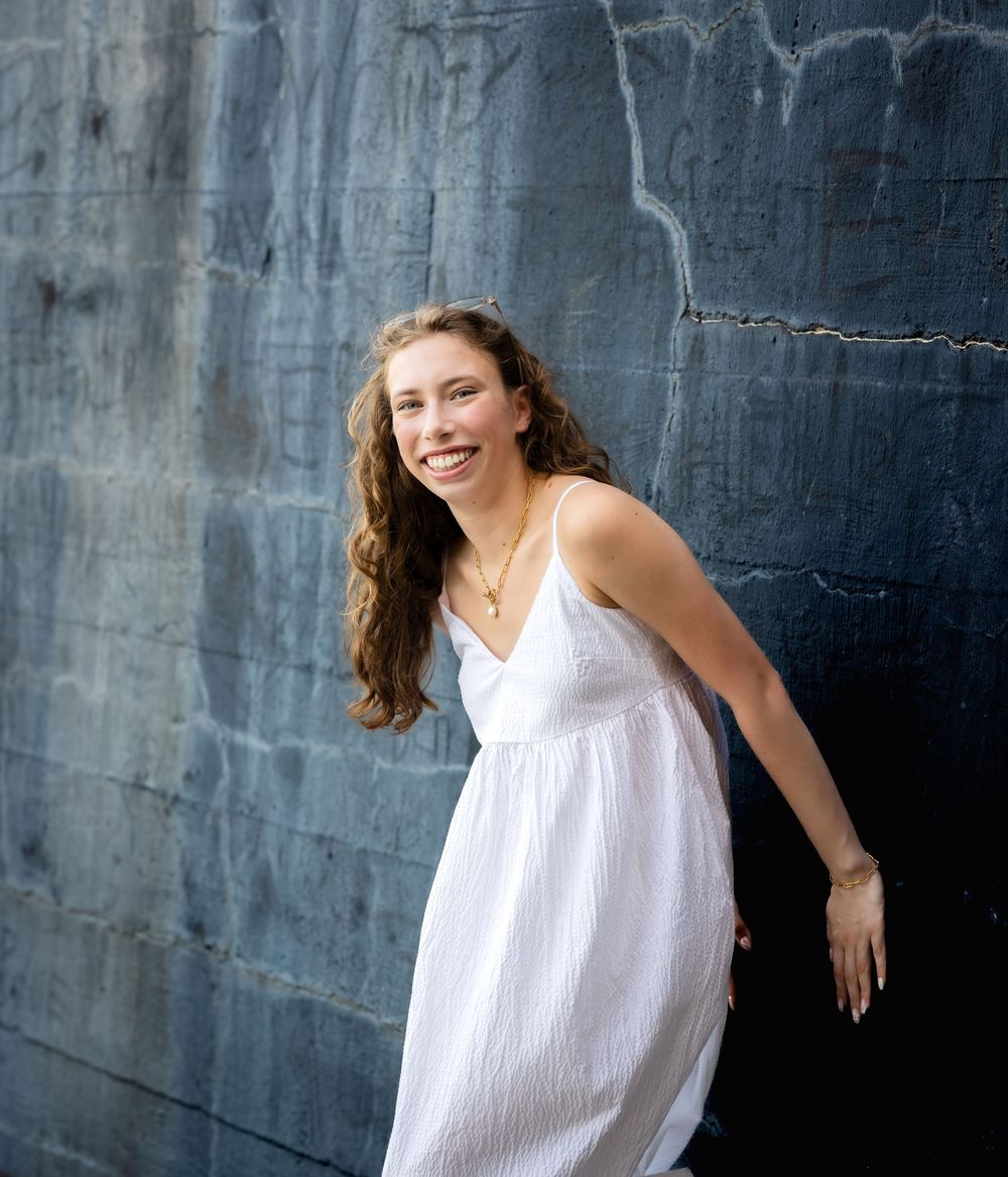 Four dynamic poses in white dress against dark textured wall showing movement and expression in studio lighting.