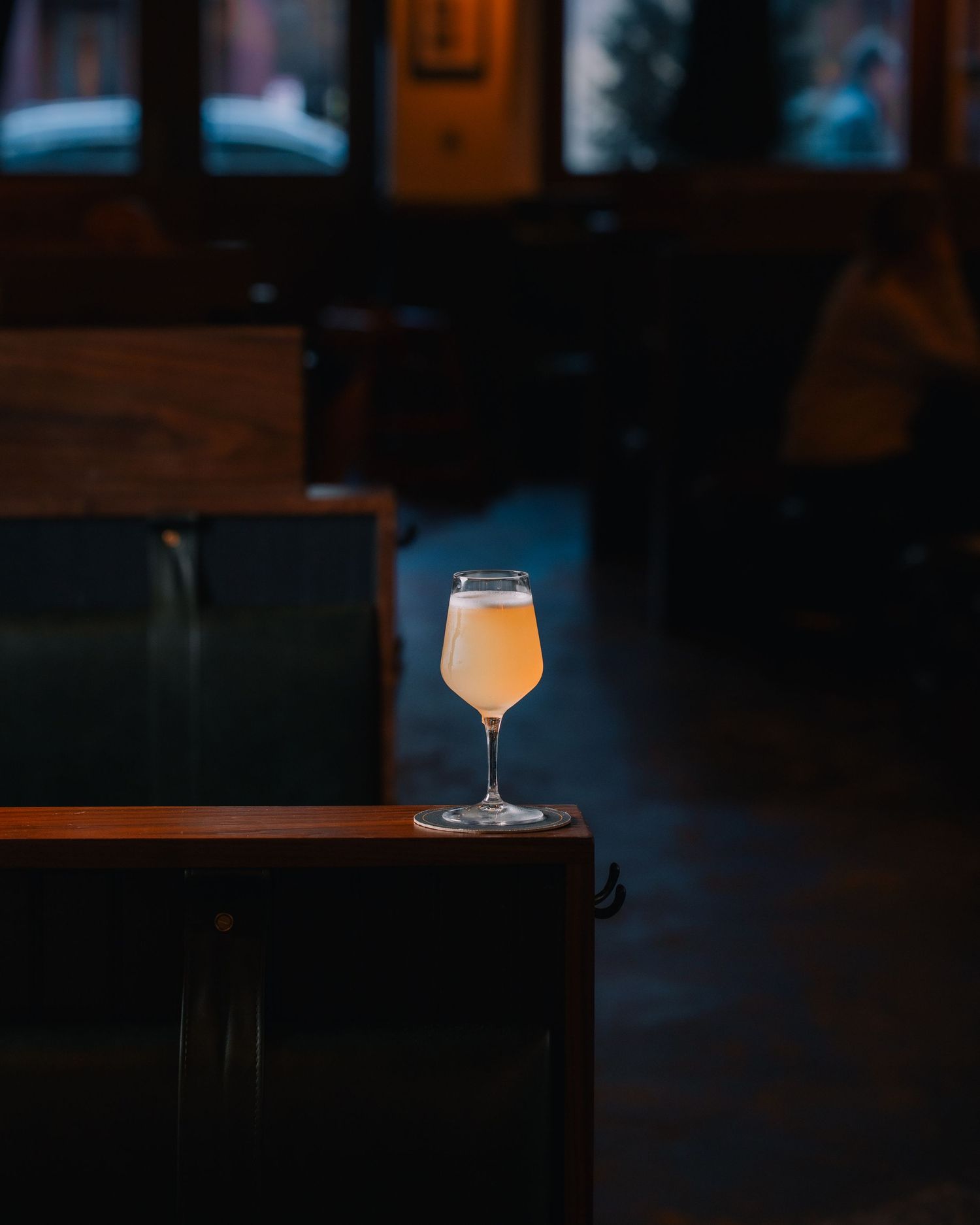Glowing cocktail glass illuminated on dark bar counter creating dramatic mood lighting effect.