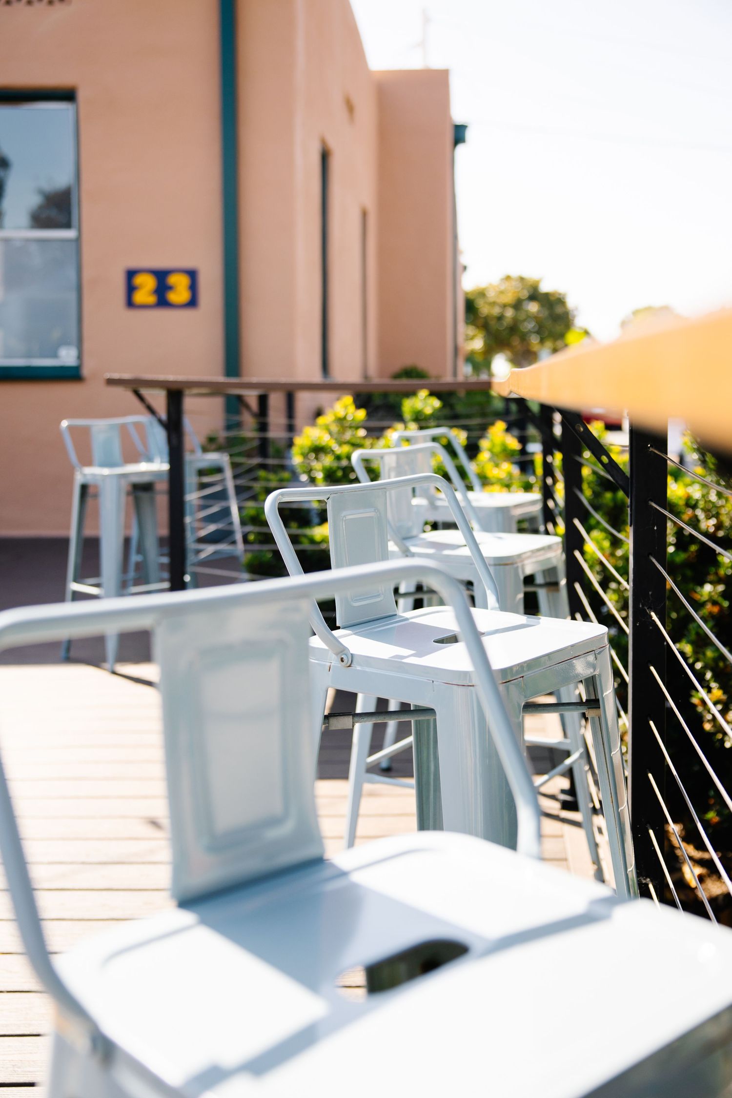 Modern outdoor patio with white chairs and metal railings at sunset.