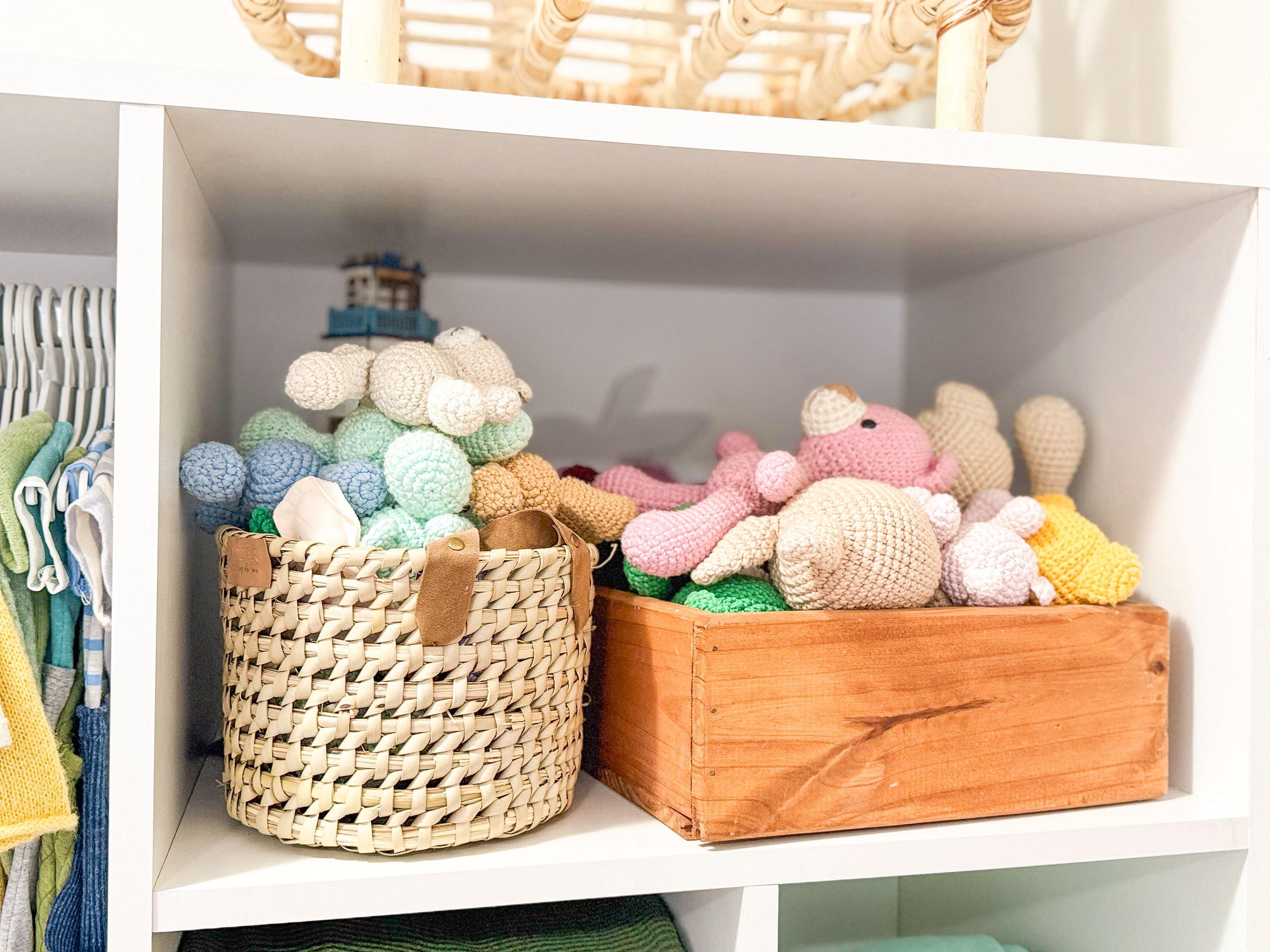 Nursery shelves with woven baskets and wooden boxes containing stuffed animals and baby accessories.