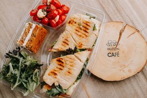Grilled flatbread sandwiches with fresh vegetables arranged in takeout containers.
