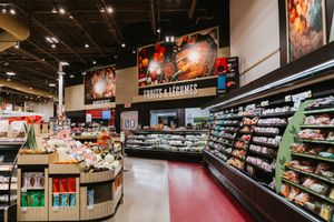 Well-stocked grocery store aisle with red floors and illuminated product displays.