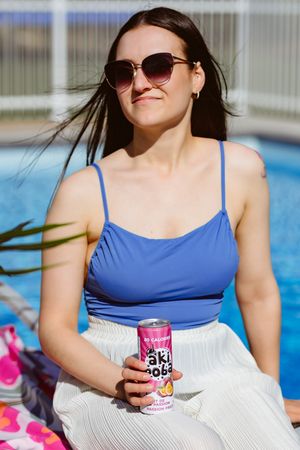 Summer poolside scene with sunglasses and canned beverage on bright day.