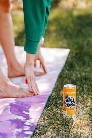 Orange soda can beside yoga mat during outdoor workout session.