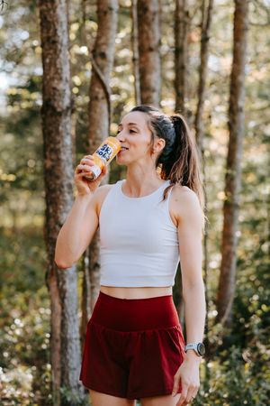 Refreshing drink moment captured in sunlit forest setting.