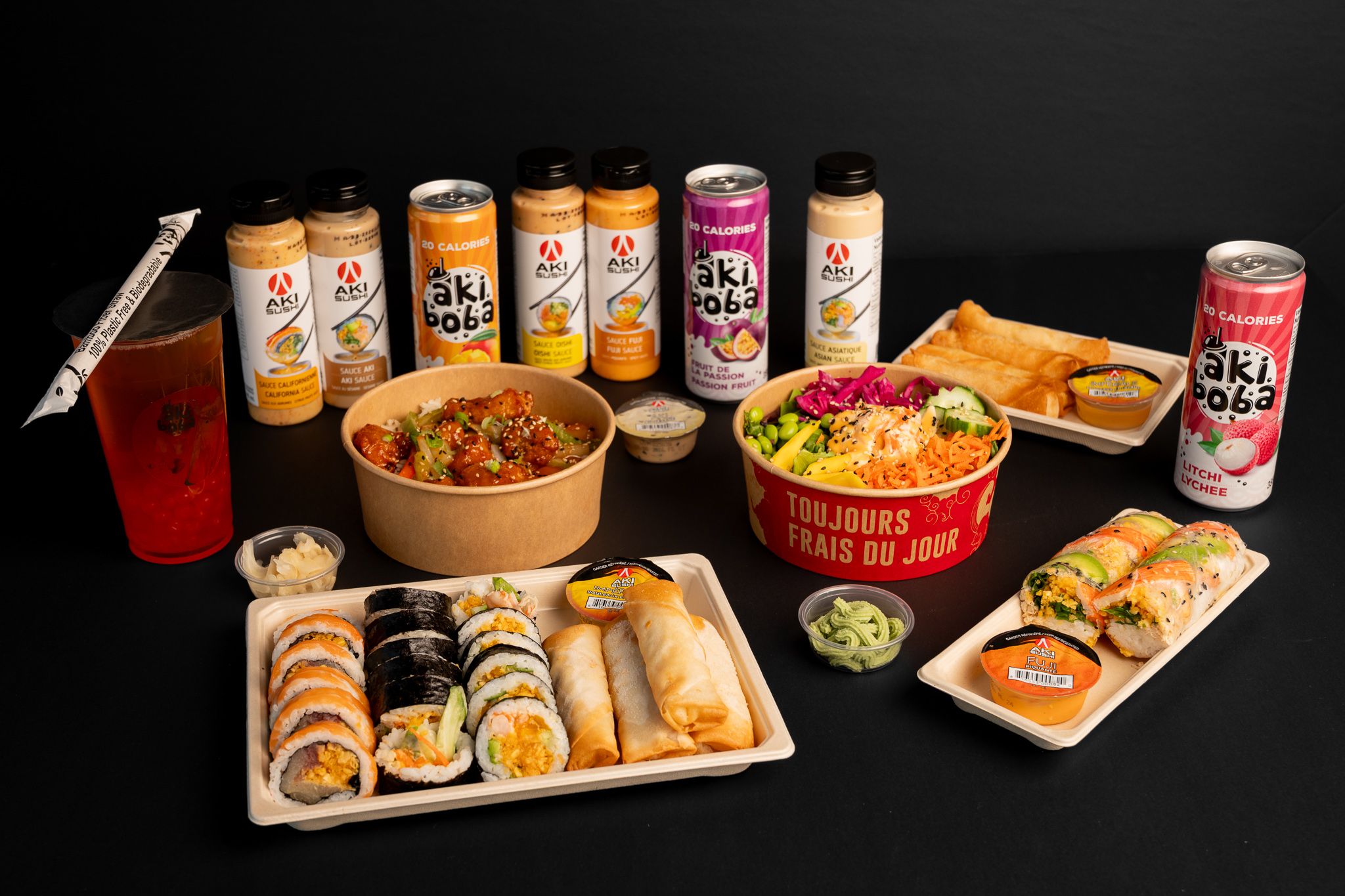 Extensive spread of Asian fusion dishes and Oki Poki drinks arranged on black surface.