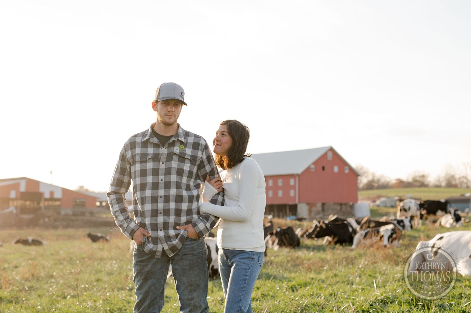 A couple shares a tender moment while standing in a grassy field on their farm.