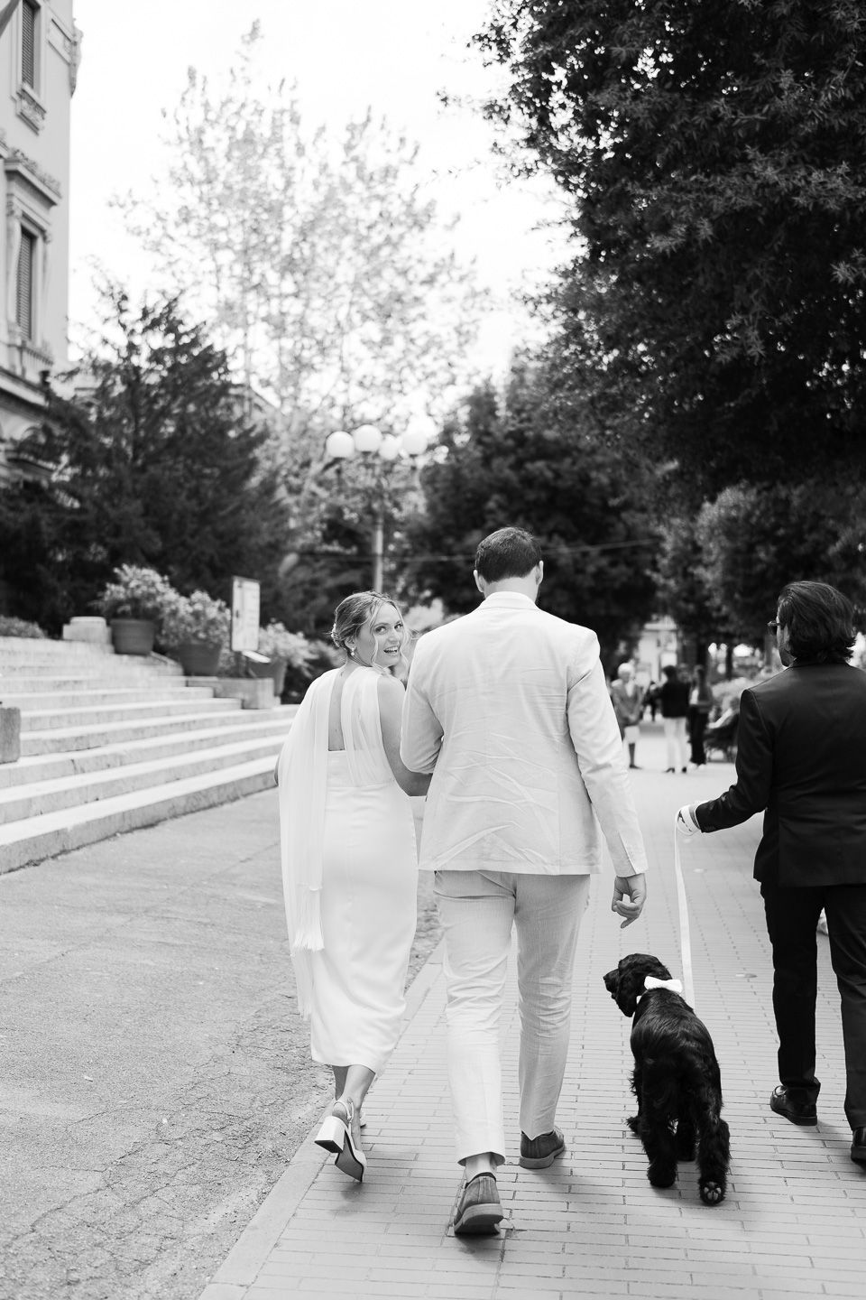Engaged couple about to get married, going to Montecatini Terme City Town Hall walking down the street with their dog