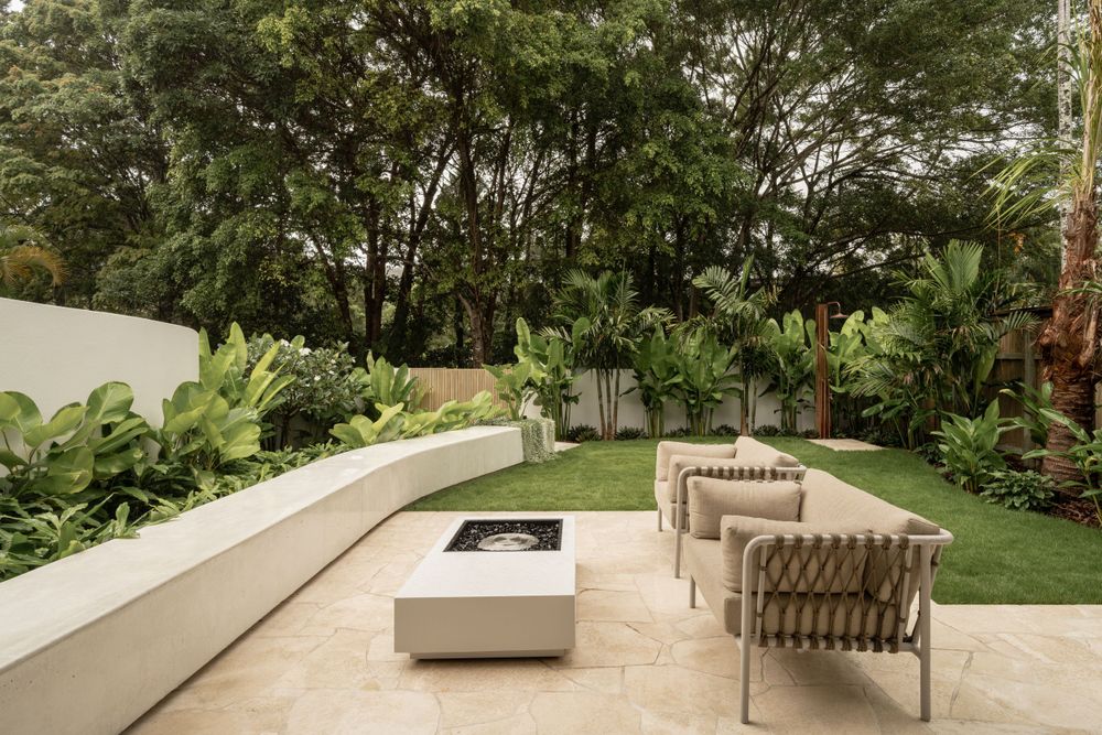 Contemporary outdoor patio with clean white seating and lush tropical garden landscaping.