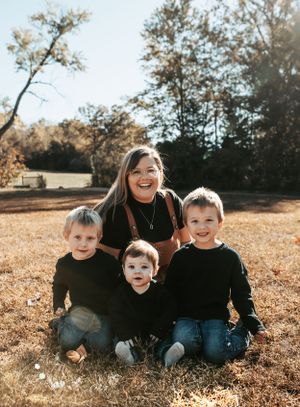 Family portrait taken outdoors on golden autumn grass with matching black outfits.