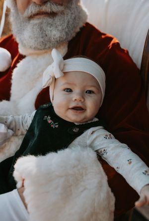 Baby wearing white winter hat and cozy outfit during holiday photo shoot.