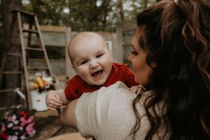 Tender family moment captured in warm tones against a natural outdoor setting.
