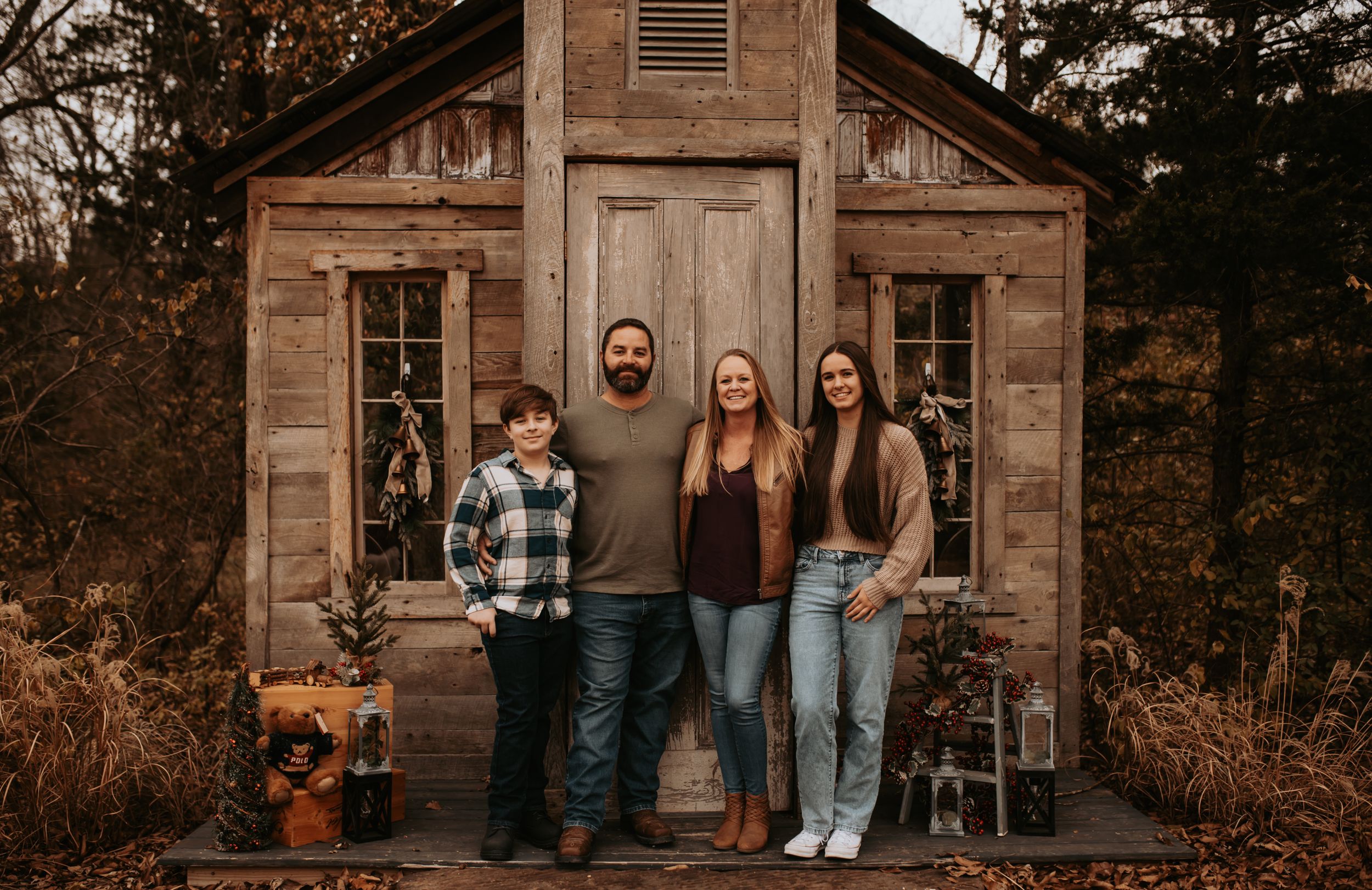 Family portrait session outside rustic wooden cabin in autumn setting.