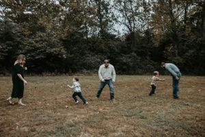 Candid family moment playing and running in an open autumn field.