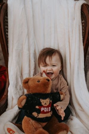 Series of photos showing a happy toddler playing with teddy bears against white backdrop.