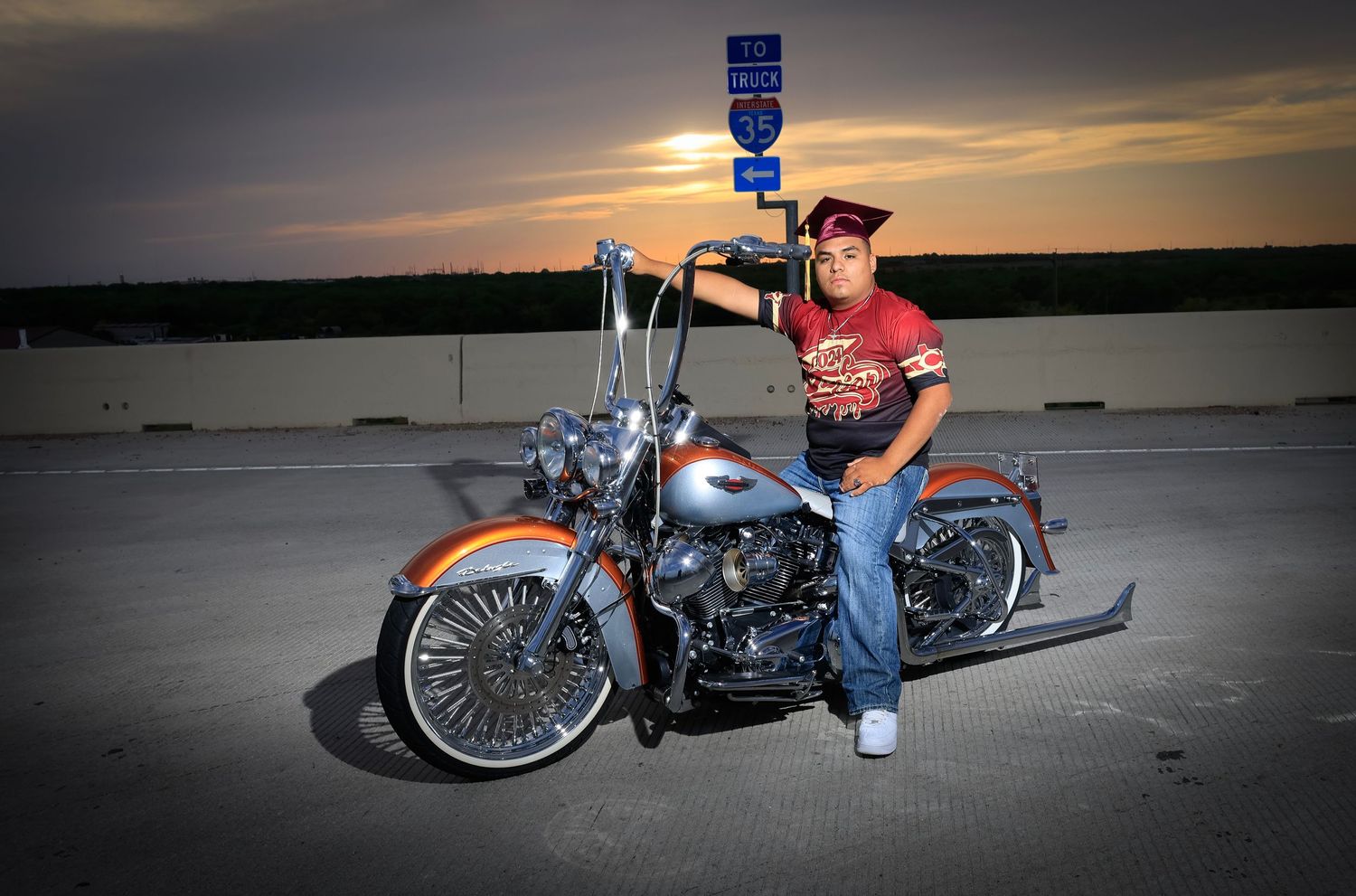 Custom motorcycle with chrome details parked at sunset against waterfront backdrop.