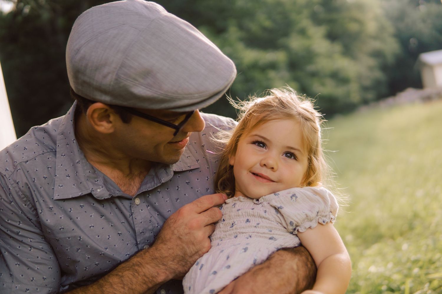 A tender outdoor moment between a father and his daughter in a floral dress.