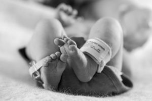 Black and white close-up of tiny baby feet with soft focus background.