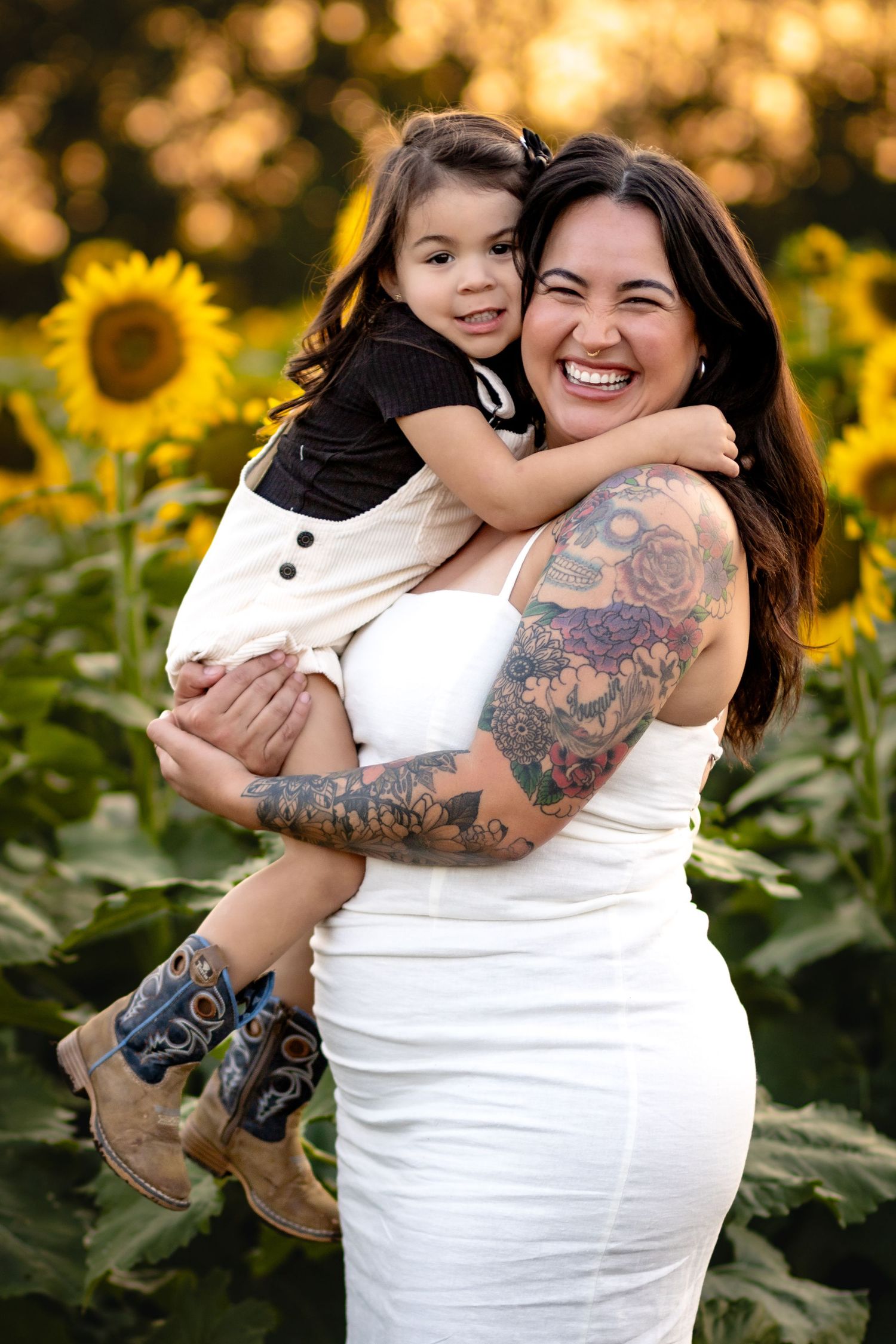 A heartwarming embrace among vibrant sunflowers as the sun sets, showcasing a white dress and colorful tattoo sleeve.