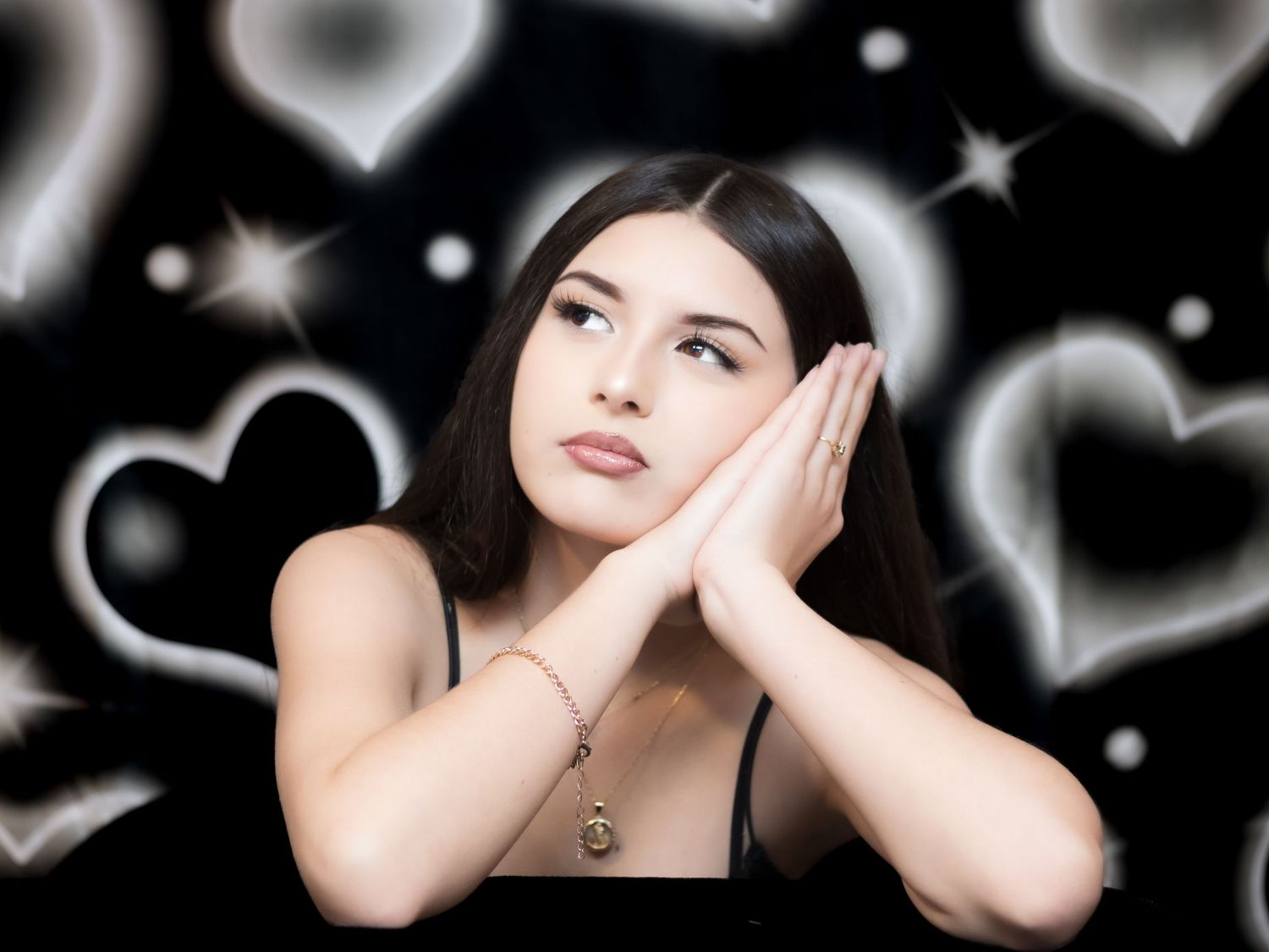 Dreamy portrait against dark background with glowing hearts and stars in black and white artistic effect.