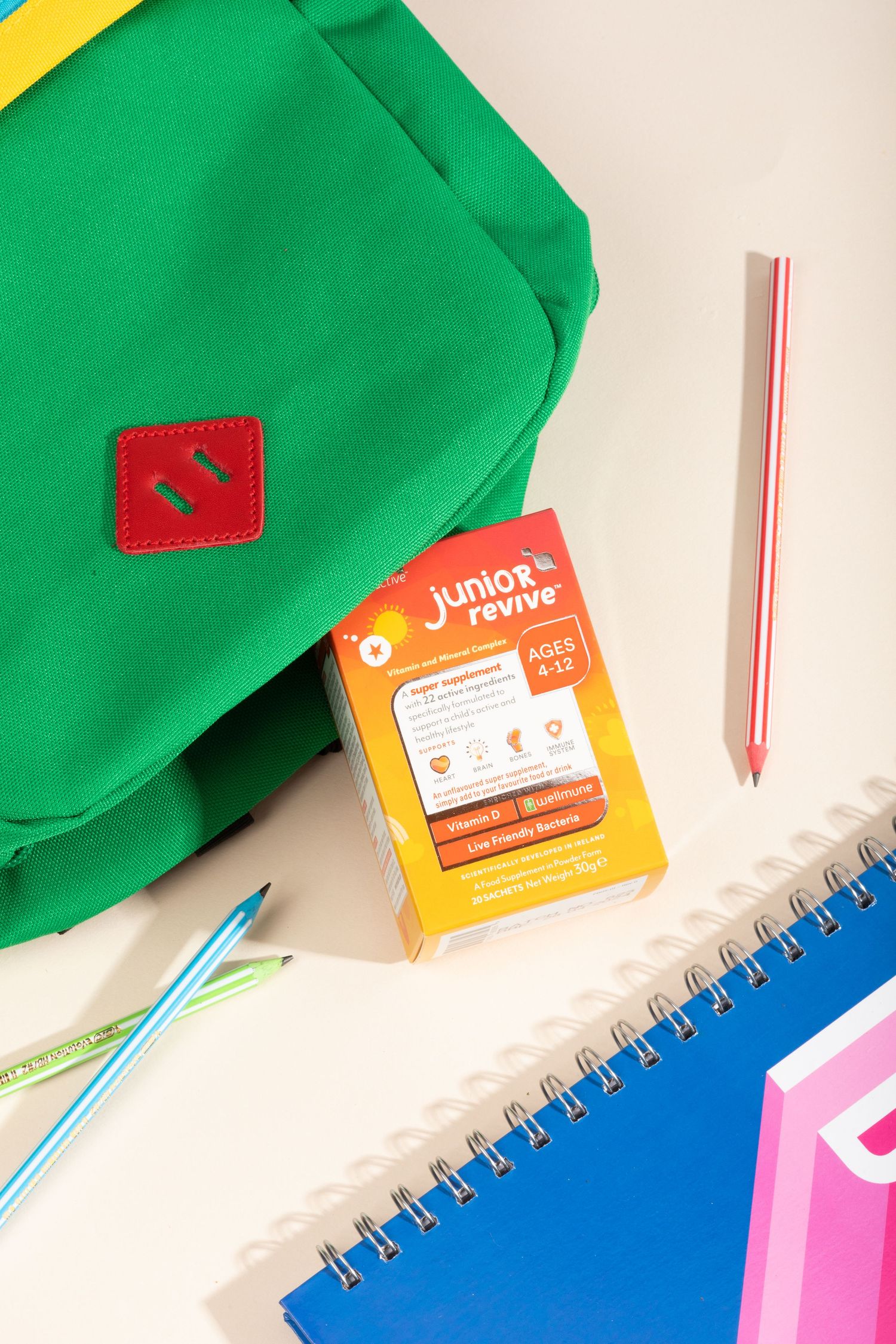Green backpack with school supplies including notebooks, pencils along with three junior supplement sachets.