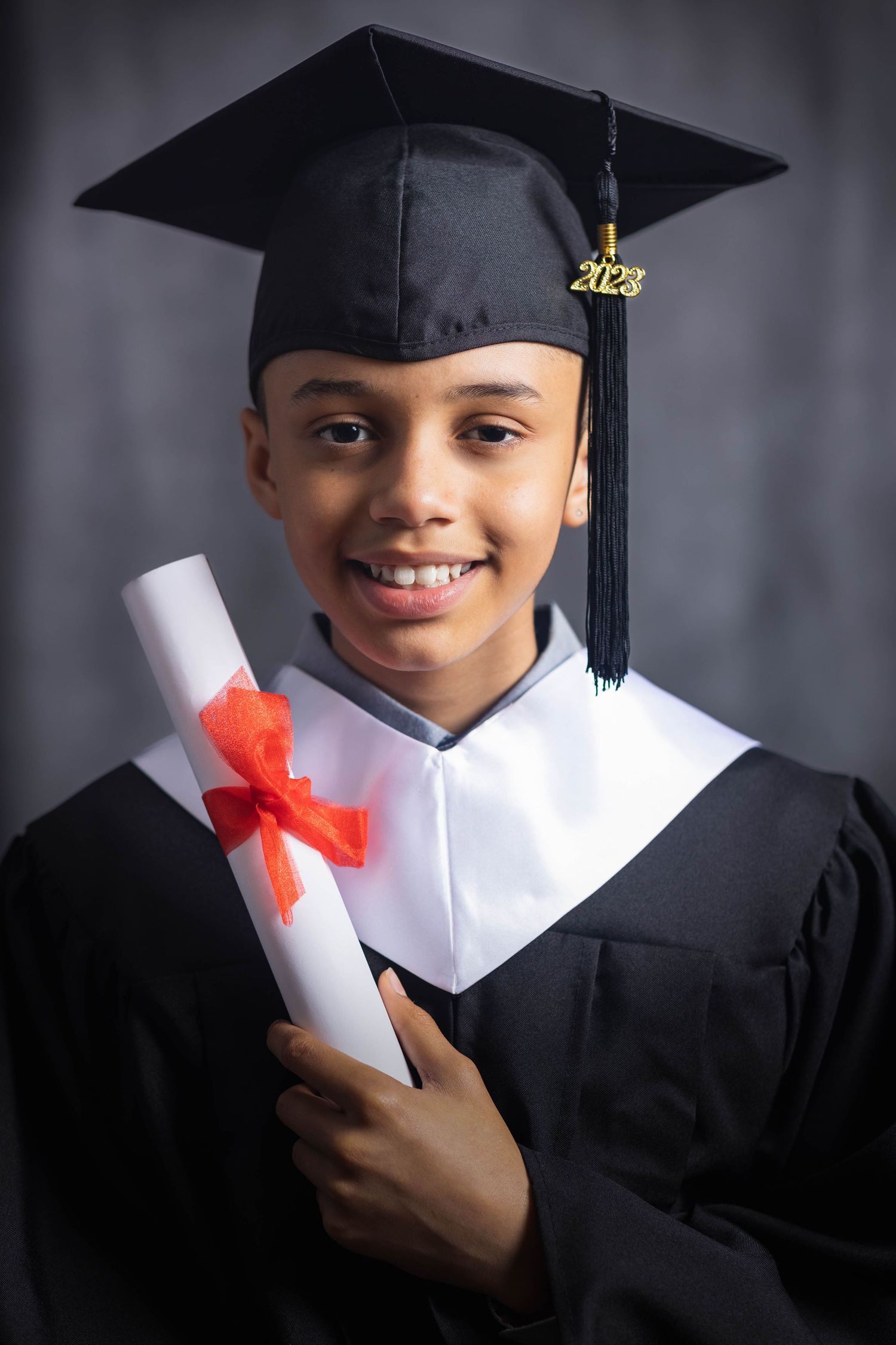 A graduate in academic regalia poses with diploma and tassel during a graduation photo session.