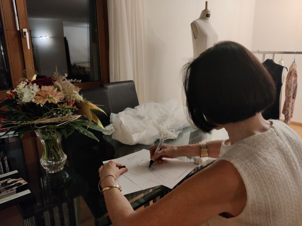 Frau zeichnet eine Skizze eines Brautkleids in einem Atelier