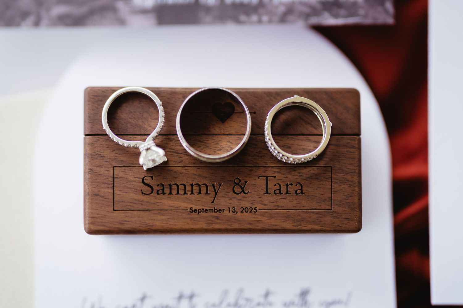 Three wedding rings displayed on a rustic wooden surface with text engraving.