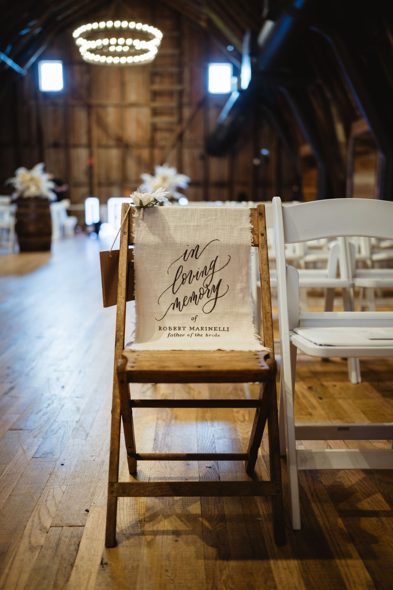 Reserved seating signs with elegant calligraphy displayed on wooden chairs at a rustic barn wedding venue.