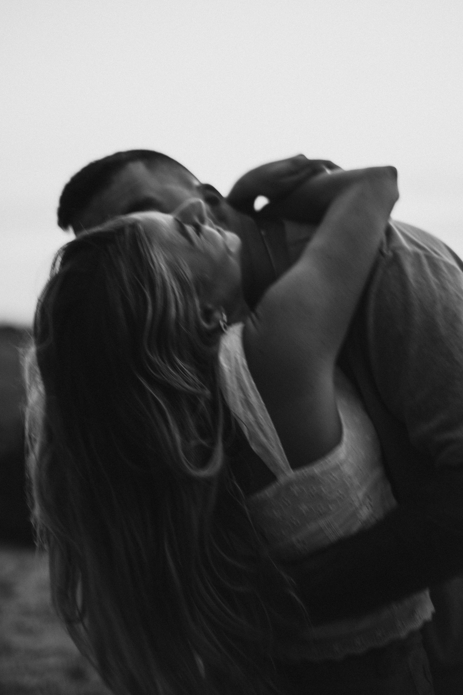 Artistic black and white portrait capturing an intimate emotional moment in dramatic lighting.