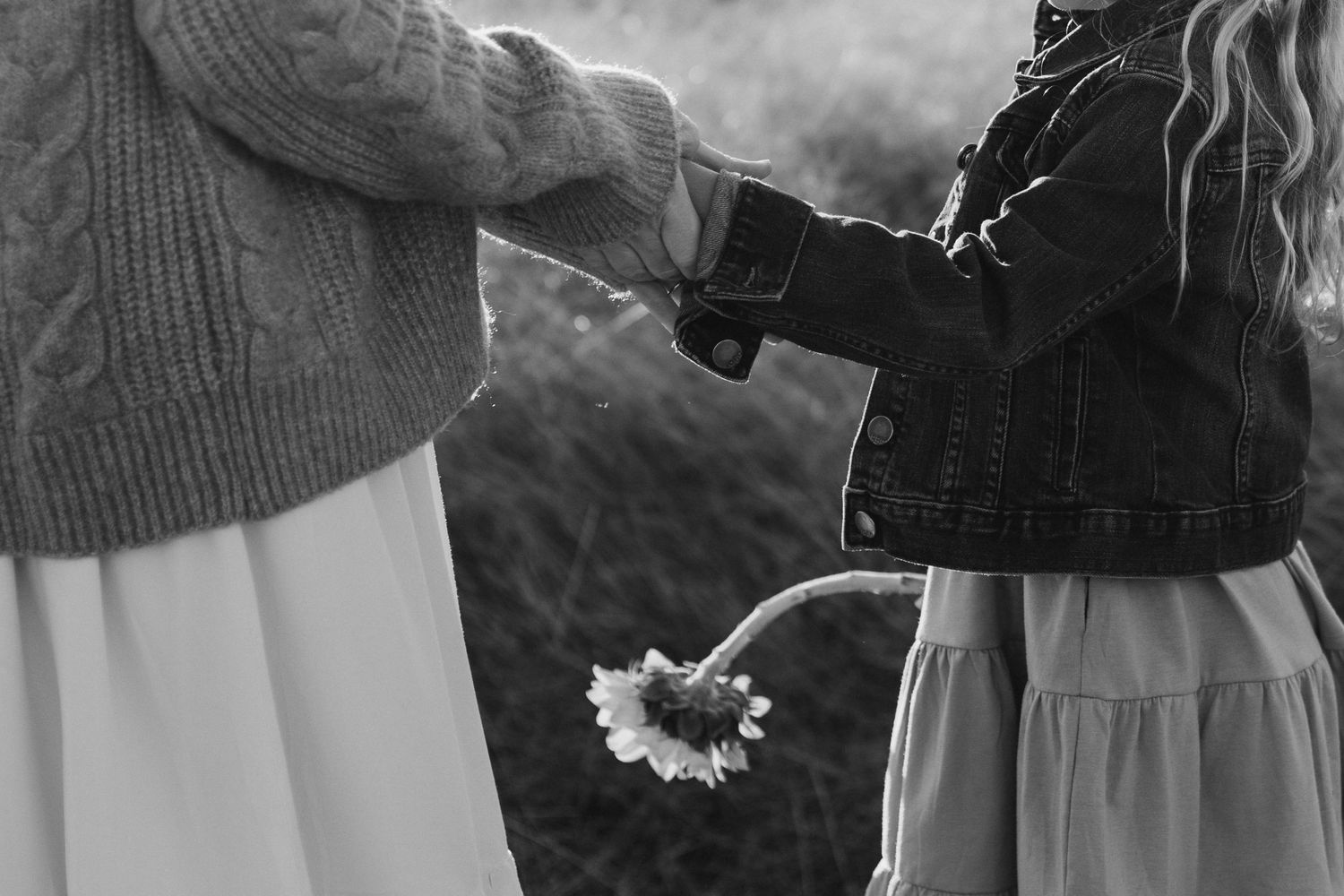 A couple in wedding attire stands together in a black and white photograph on their special day.