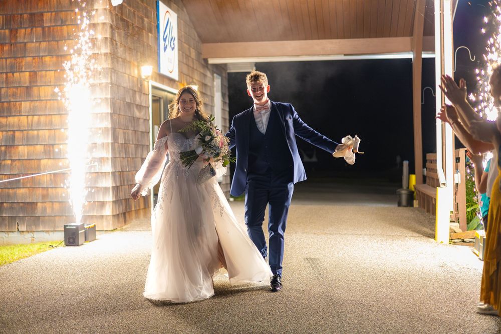 Elegant wedding couple walking along a dimly lit brick corridor with warm lighting illuminating their path.