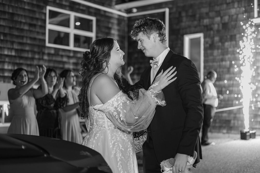 Couple shares a slow dance at wedding reception with brick walls and sparkler lights glowing in the background.