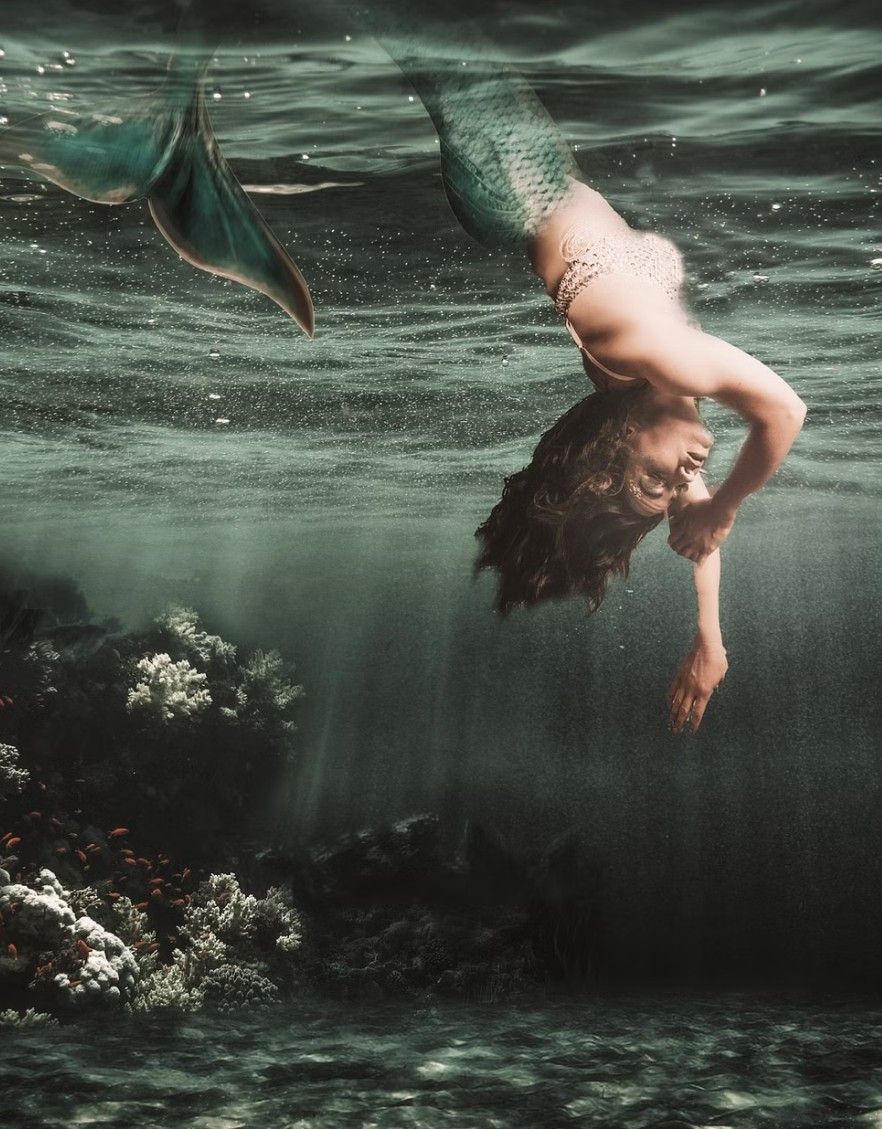 Ethereal underwater photography with figure submerged in dark teal waters.