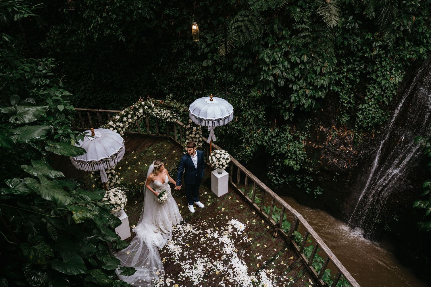 Elegant outdoor wedding ceremony setup with white lanterns and floral decorations in a garden.