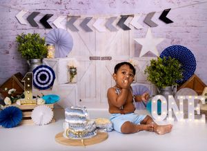 Cake smash photo collage showing blue and white themed birthday decorations and a small child enjoying their first birthday.