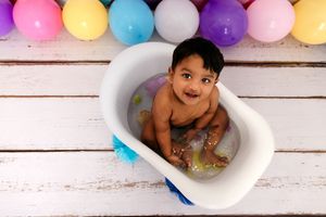 Colorful party balloons in pink, yellow, blue and purple decorating a white wooden background.