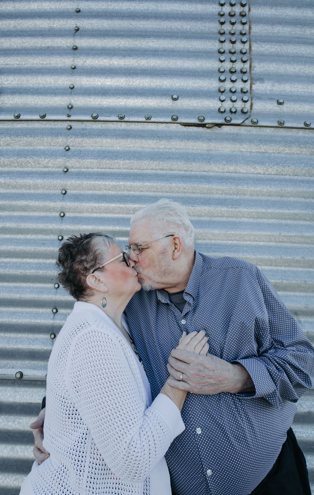 Intimate moment shared between couple against metallic background.