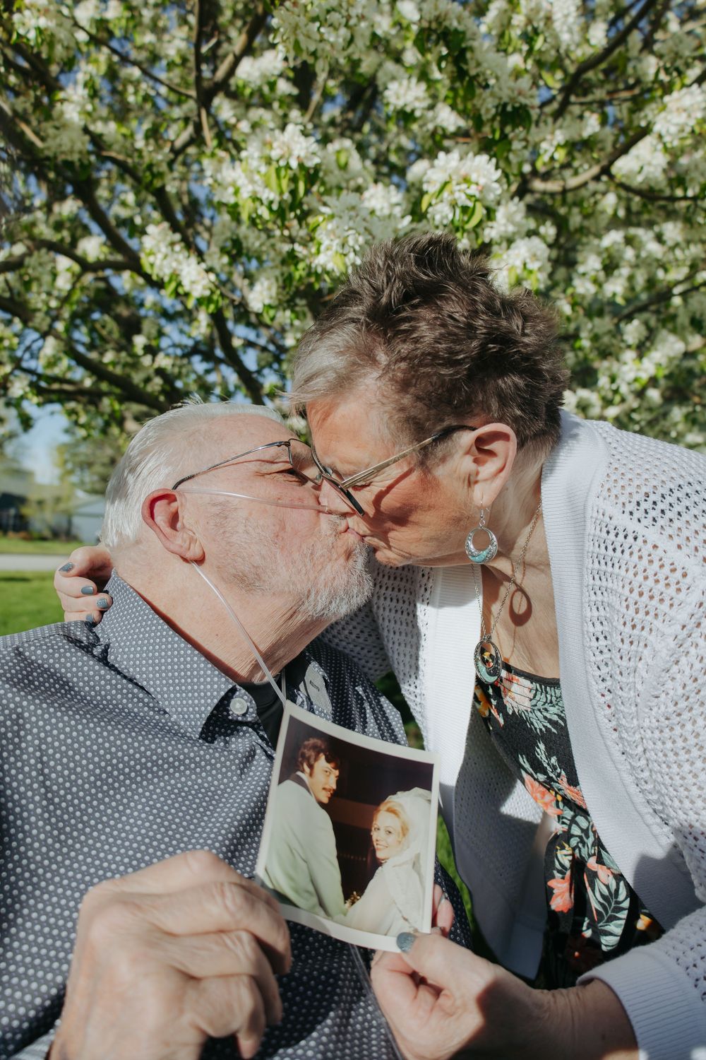 Couple sharing romantic kiss under blooming spring trees.