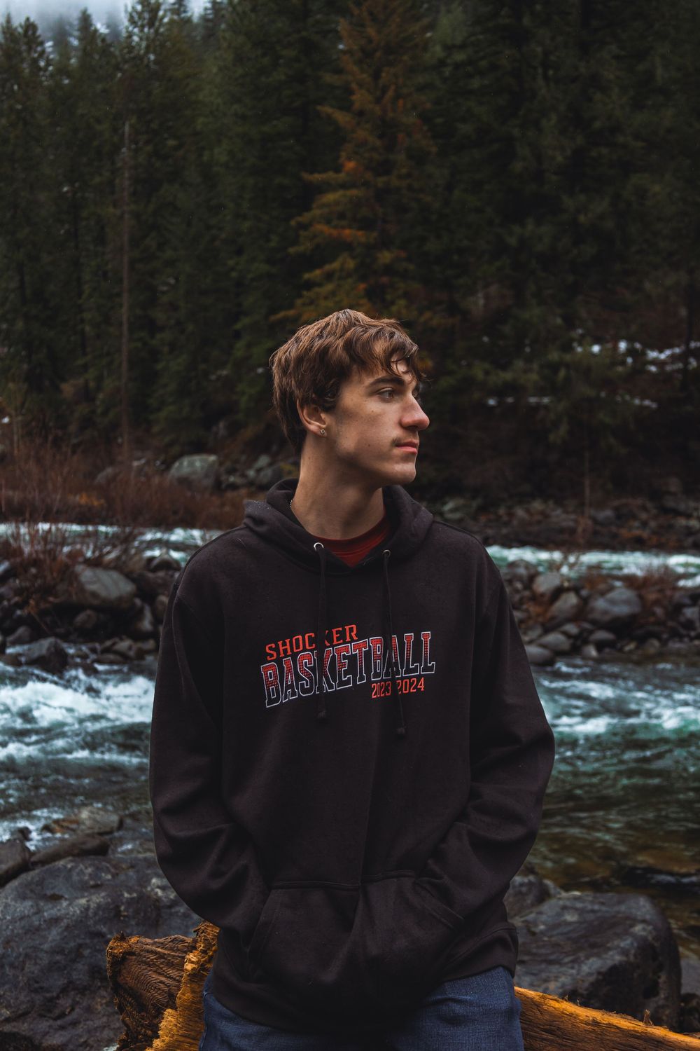 A scenic winter riverside with evergreen trees and snow-covered rocks in the Pacific Northwest.