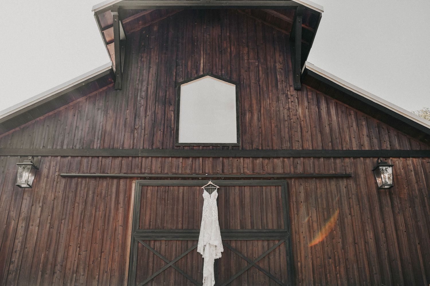 rustic barn of whispering oaks with bridal gown hanging on it