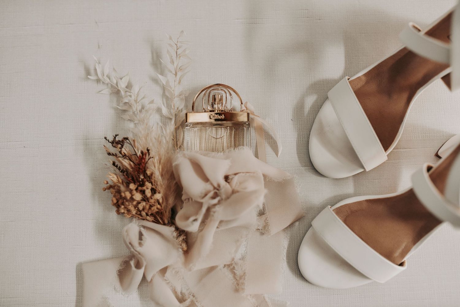 Flat lay of elegant bridal details with lace veil, wedding rings, and boho florals