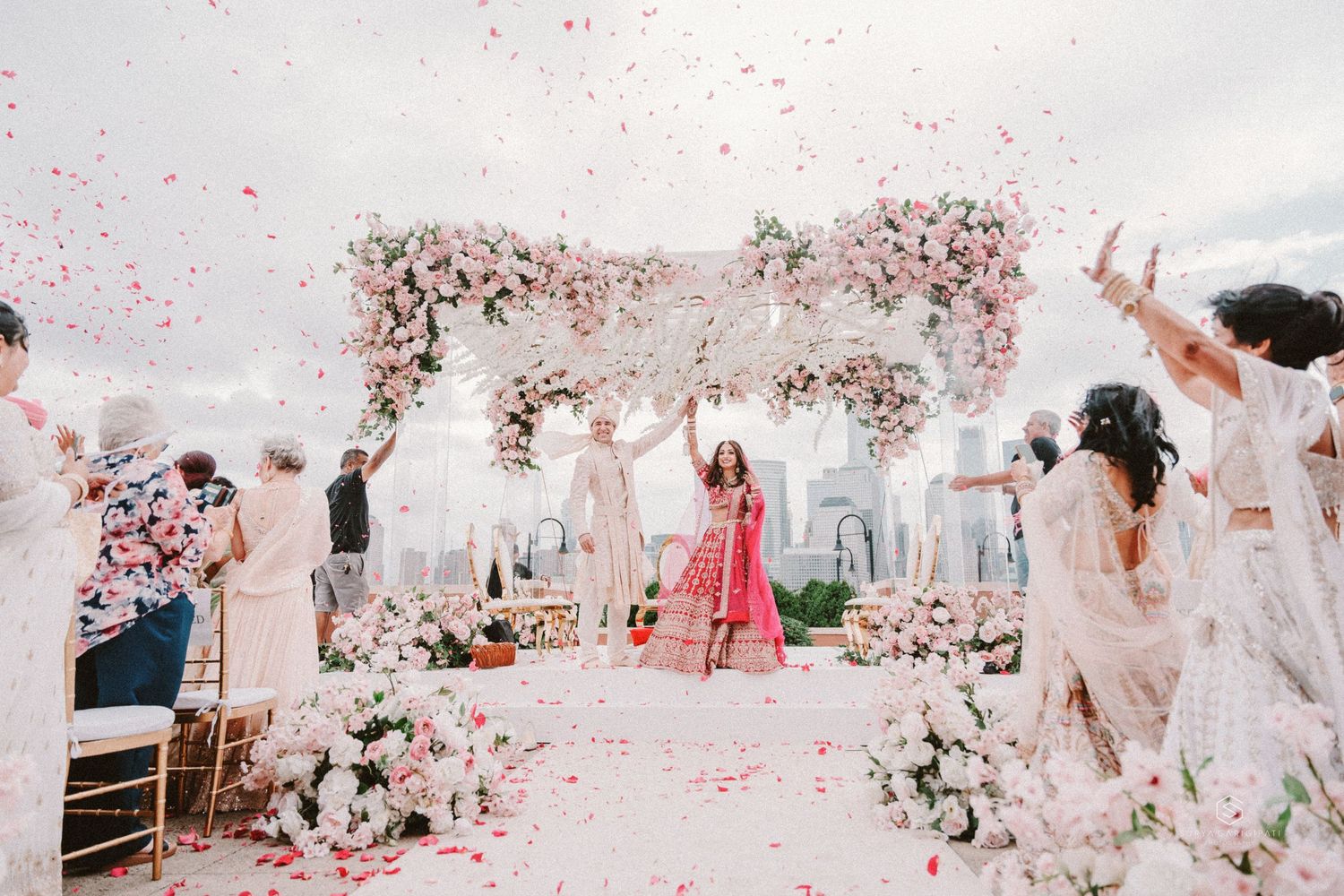 A group celebrates with pink confetti cannons creating a joyful shower of confetti in an indoor event space.