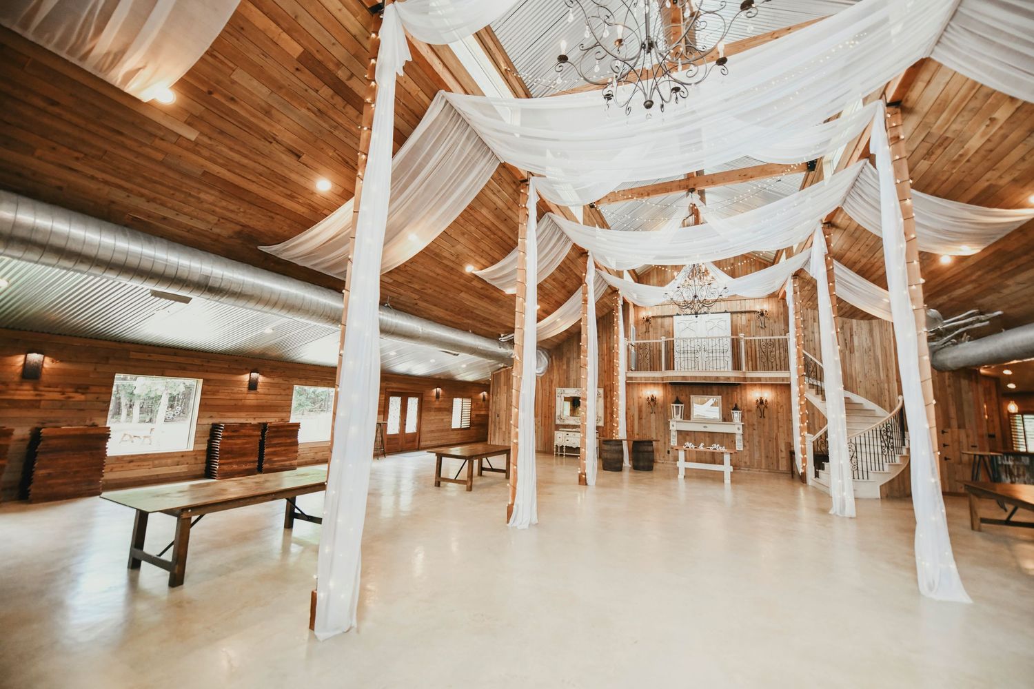 Modern barn wedding venue with white curtains flowing in the breeze and natural light pouring through large windows at whispering oaks