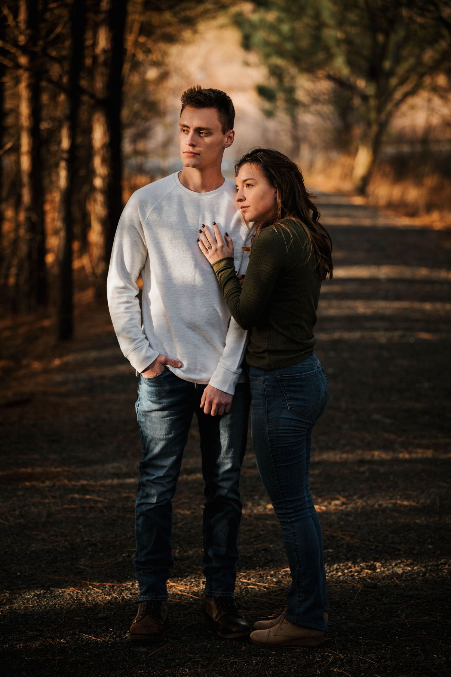 A couple shares a tender moment at sunset in a wooded area.