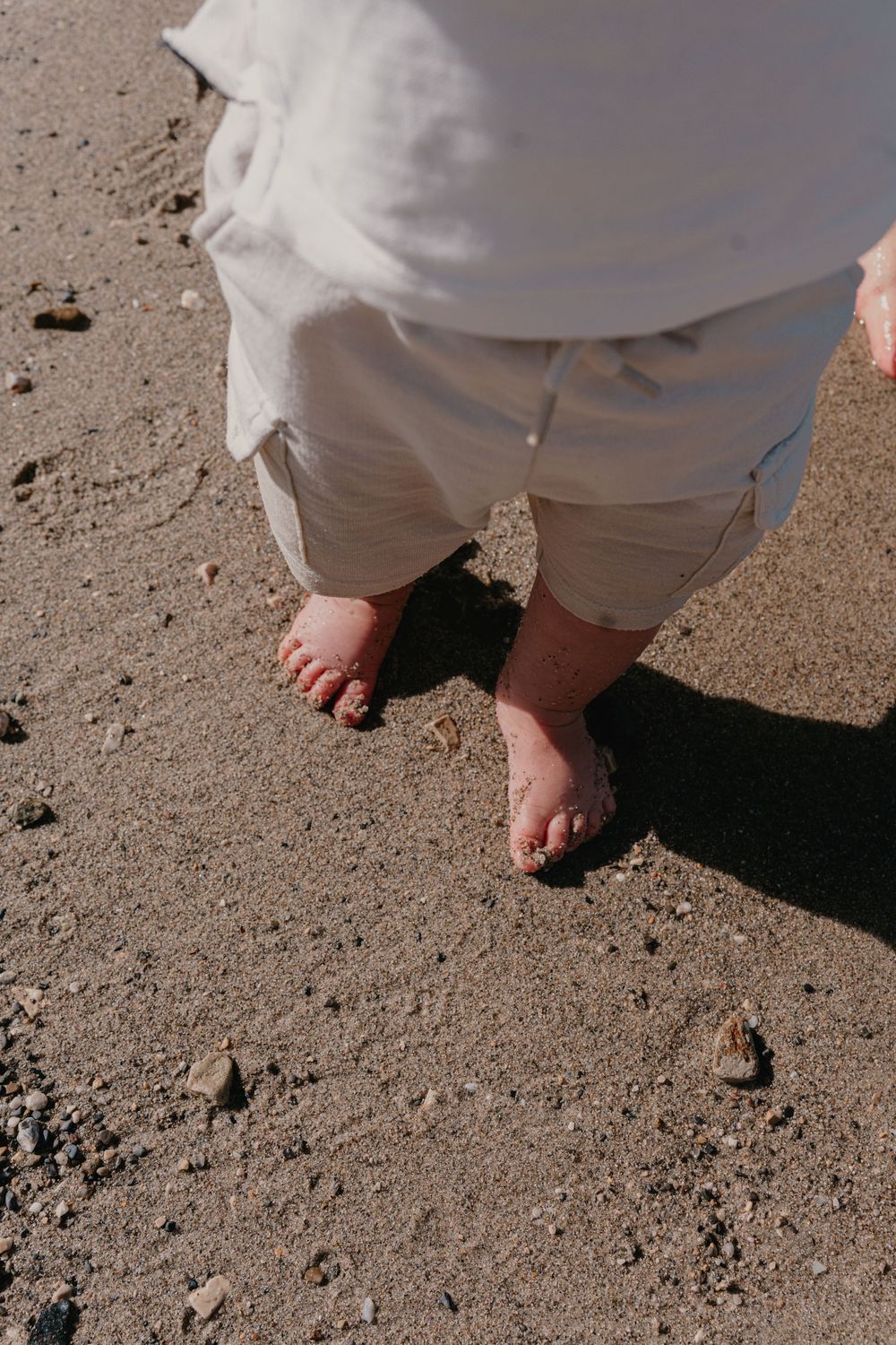 dÉTAIL DE PIED D'UN BÉBÉ marchant sur le sable lors d'une séance photo famille, photographe famille et mariage.