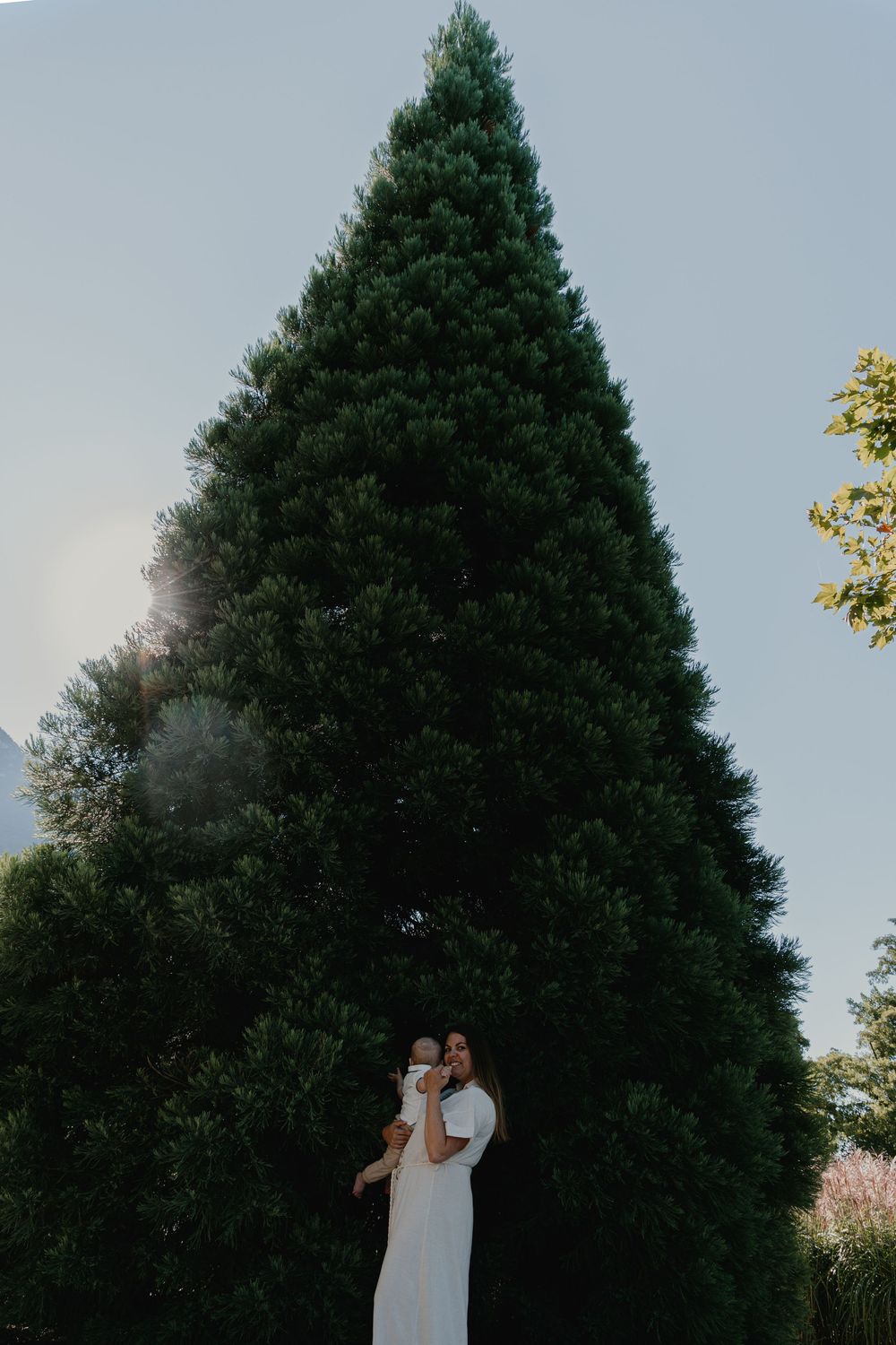 Une maman et son bébé devant un sapin dans un moment de délicatesse lors d'une séance photo famille à Annecy.