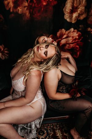 Sensual boudoir photography series featuring artistic poses against dark backdrop with red floral accents in moody lighting. Grand Rapids Bo
