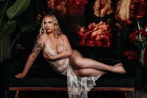 Artistic boudoir photography in moody dark setting with red flowers and dramatic lighting. Grand Rapids Boudoir Studio