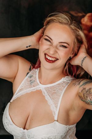 Glamour portrait featuring soft poses and expressions in white lace bodysuit with moody lighting. Grand Rapids Boudoir Photography
